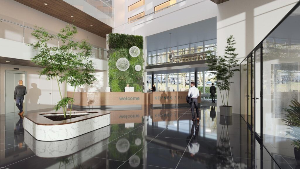 Moderne en lichte ontvangsthal van het John M. Keynesplein met een groene muur, balie en kantoorbezoekers.